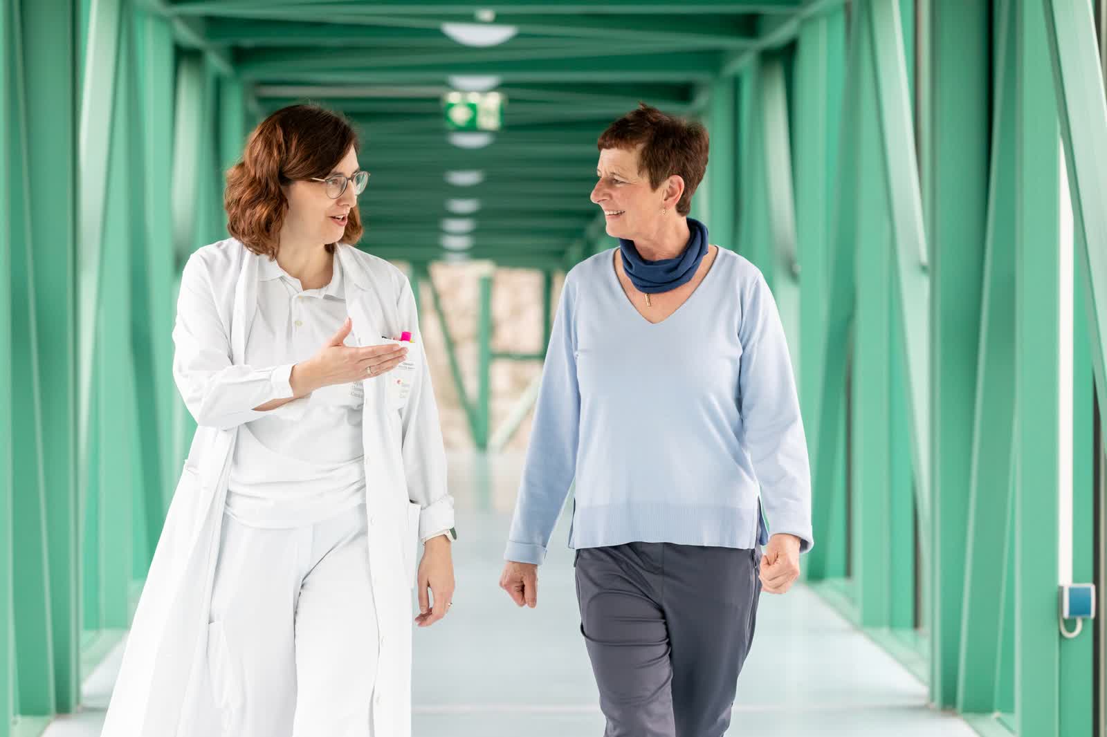 Prof. Dr. med. Sabine Altrichter im Gespräch mit Patientin Adelheid Huemer im Klinikflur