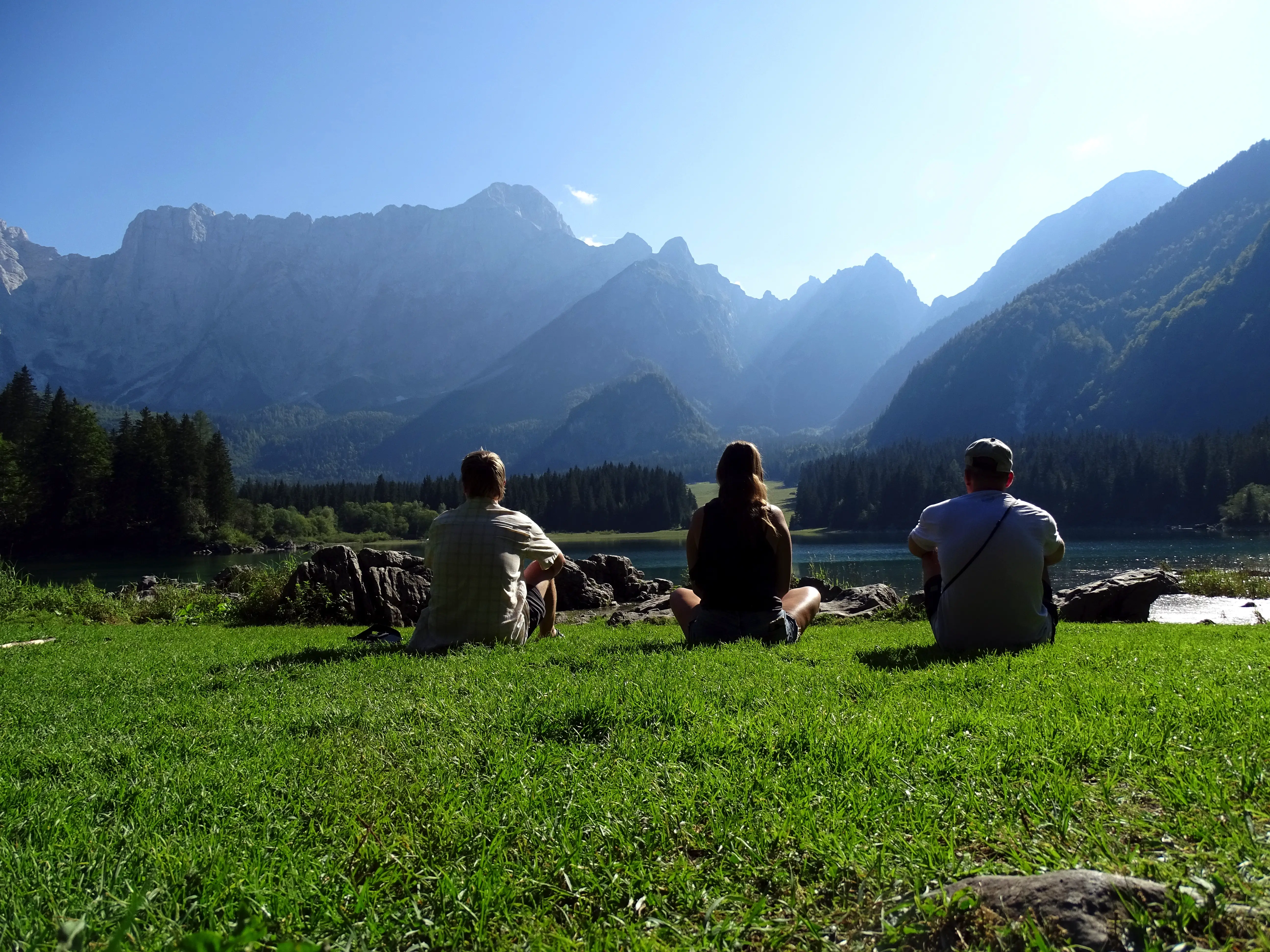 Freunde sitzen auf einer Wiese mit Bergblick