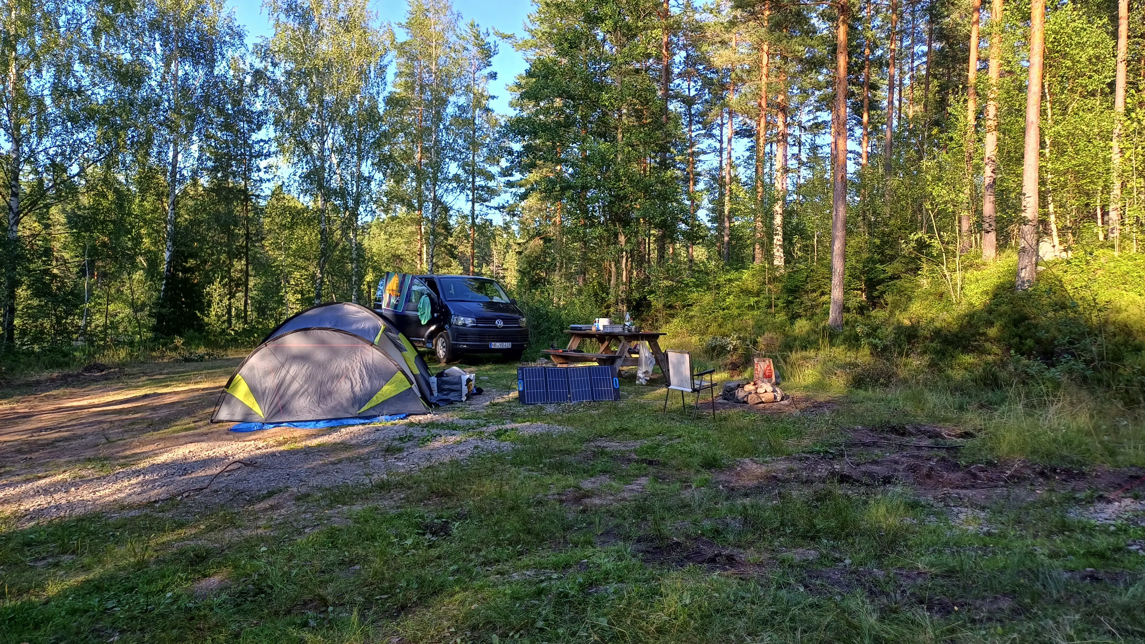 Stellplatz mit Zelt und Camper im Wald
