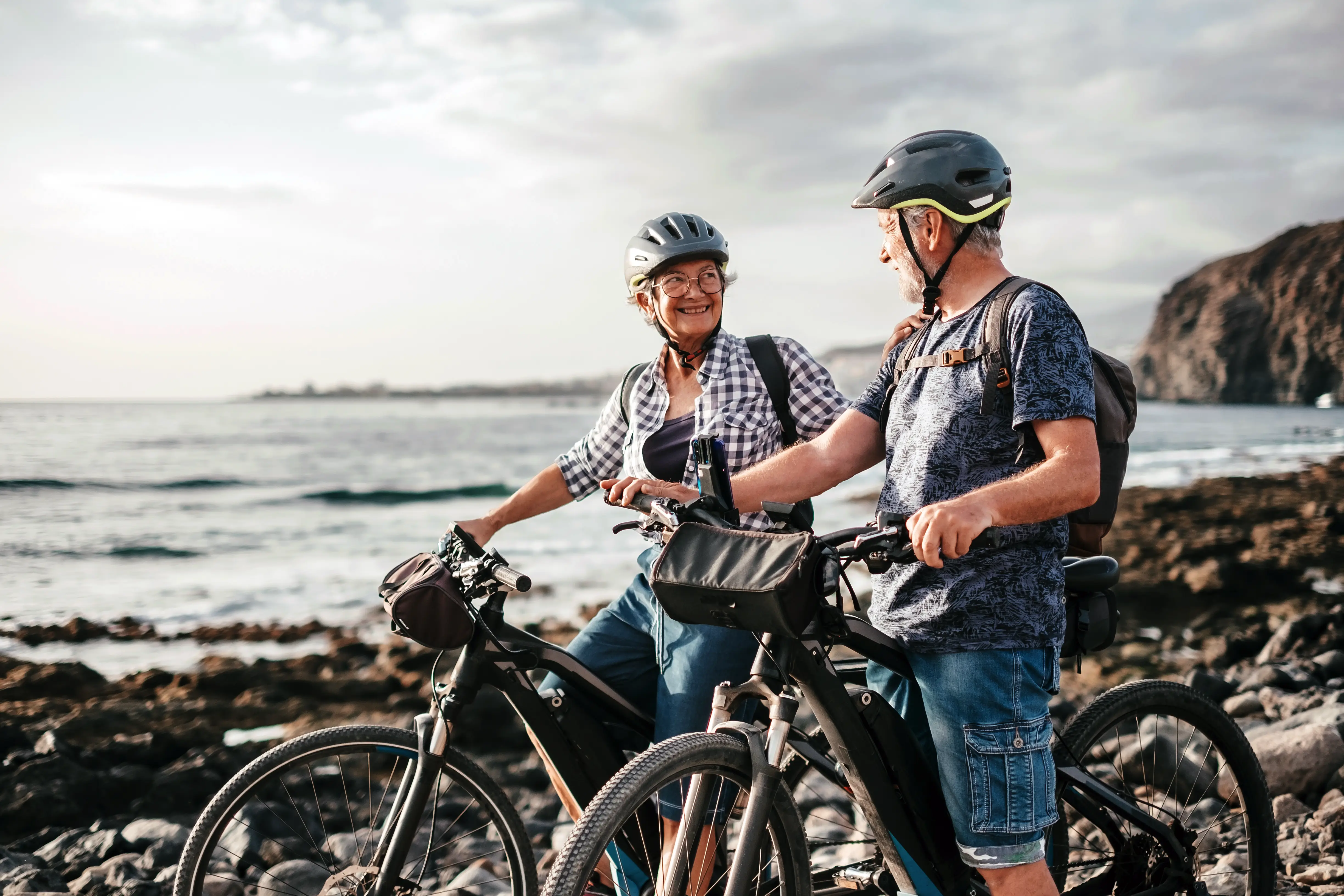 Paar mit E-Bikes an der Küste